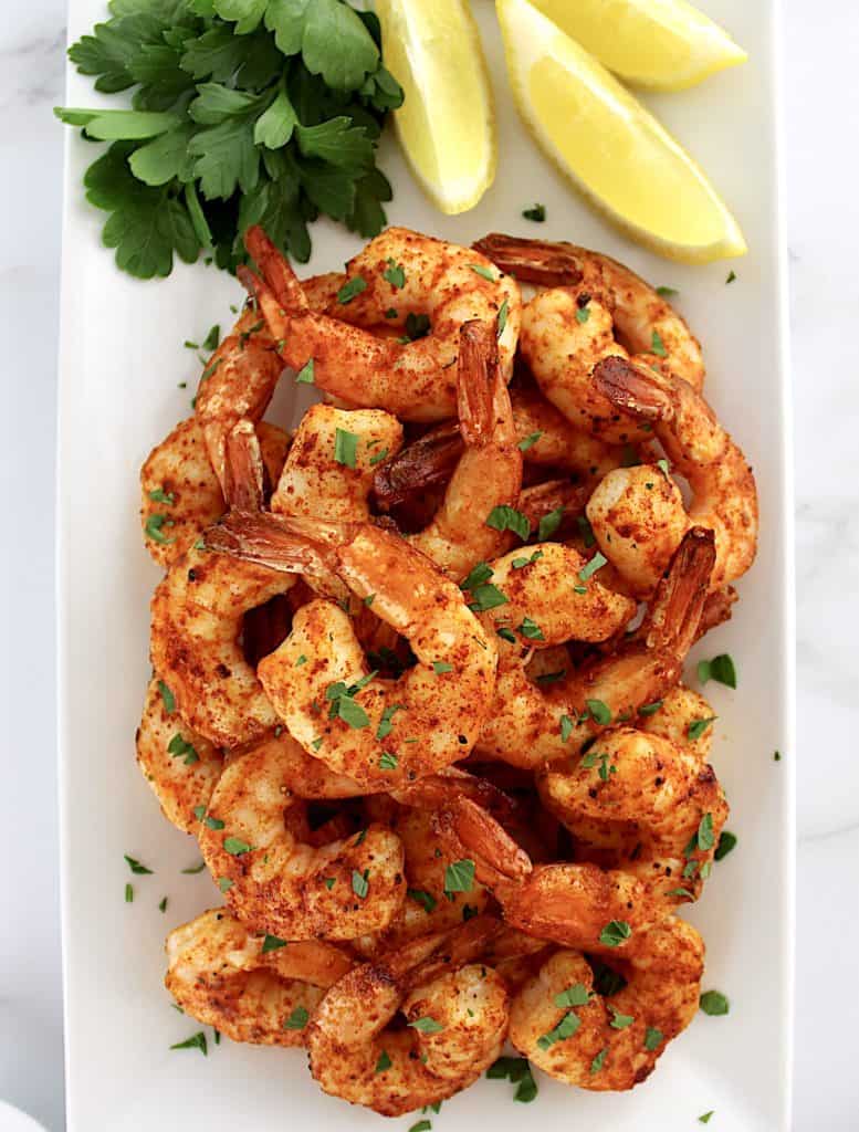 Air Fryer Frozen Shrimp on white plate with lemon and parsley on side