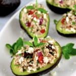Greek Tuna Stuffed Avocados on white plate with fresh mint sprigs
