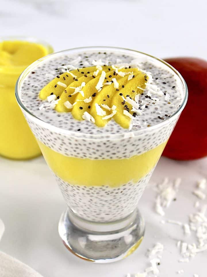 Mango Coconut Chia Pudding layered in glass with sliced mango and shredded coconut on top