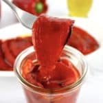 Roasted Red Peppers in open glass jar with one held up with fork