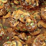 closeup of Salisbury Steak in skillet with gravy and mushrooms on top