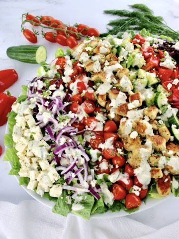 Greek Chicken Salad on white oval platter with creamy dressing drizzled on top