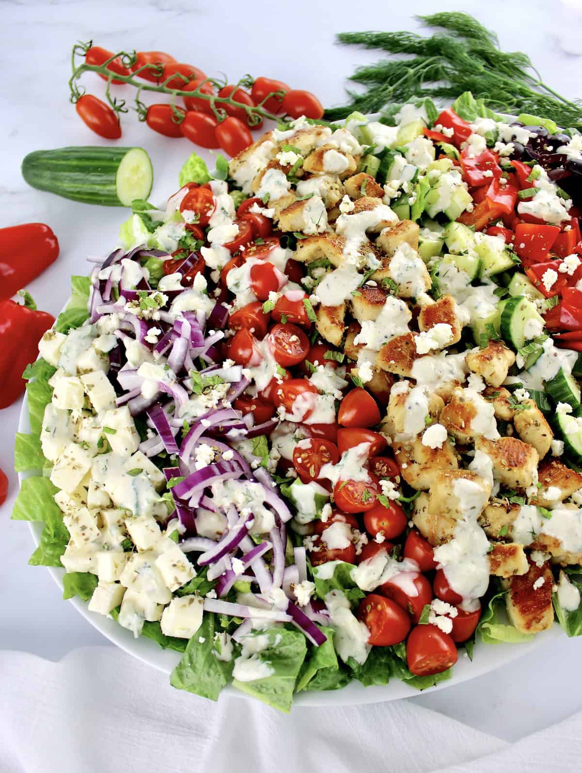 Greek Chicken Salad on white oval platter with creamy dressing drizzled on top