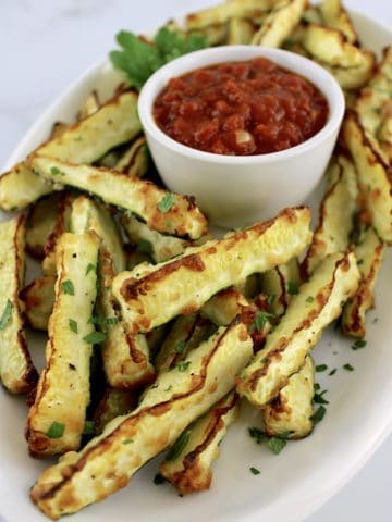 Baked Parmesan Zucchini Fries on white oval plate with side of marinara sauce