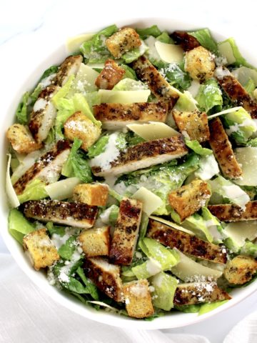 Chicken Caesar Salad in white bowl with strips of chicken and croutons