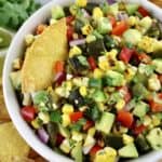 Roasted Corn and Poblano Salsa in white bowl with tortilla chip