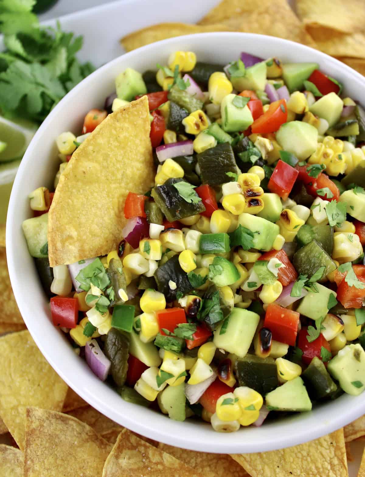 Roasted Corn and Poblano Salsa in white bowl with tortilla chip