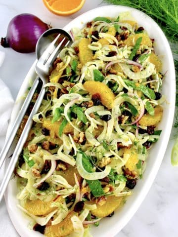 Shaved Fennel Salad on white oval plate with serving fork and spoon on side