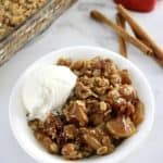 Gluten-Free Apple Crisp in white bowl with scoop of vanilla ice cream on side