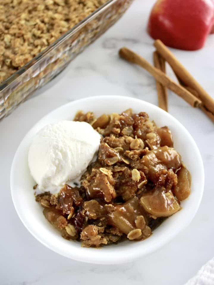 Gluten-Free Apple Crisp in white bowl with scoop of vanilla ice cream on side