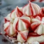 closeup of Peppermint Meringue Cookies stacked up on snowflake plate