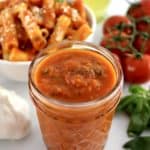 Roasted Tomato Sauce in open glass jar with pasta and tomatoes in back