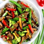 Beef Stir Fry in white bowl with cauliflower rice and veggies on side