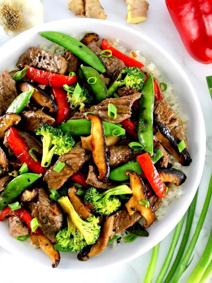 Beef Stir Fry in white bowl with cauliflower rice and veggies on side