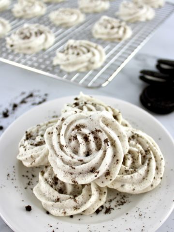 Sugar-Free Cookies and Cream Meringues in white bowl with cookies and more meringues in back on cooling rack